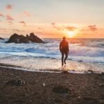 man walking in beach during golden hour