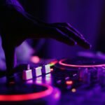 selective focus silhouette photography of man playing red-lighted DJ terminal